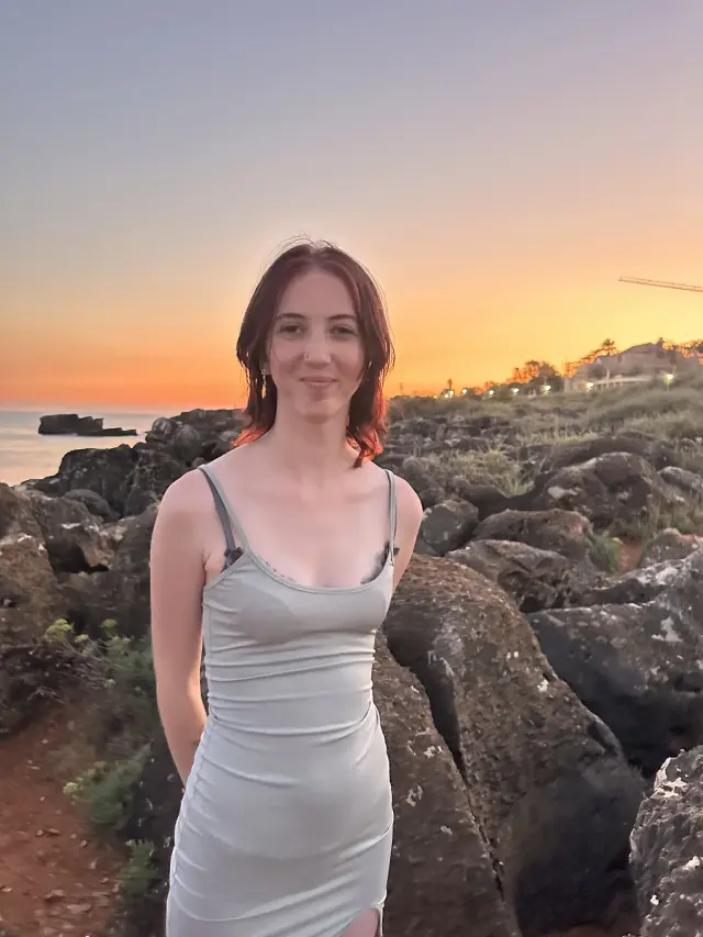 Georgie smiling by the coast at sunset